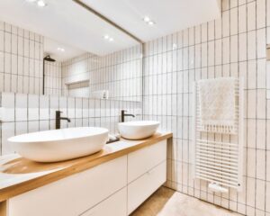 A white tiled bathroom with two sinks and a countertops in the city.