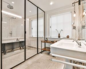 A glass tub to shower enclosure in a white bathroom.