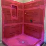 A bathroom remodel in progress featuring a shower enclosure with pink waterproofing membrane applied to cement board walls and floor.