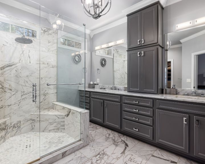 A bathroom with marble counter tops and a walk in shower featuring city-inspired cabinets.