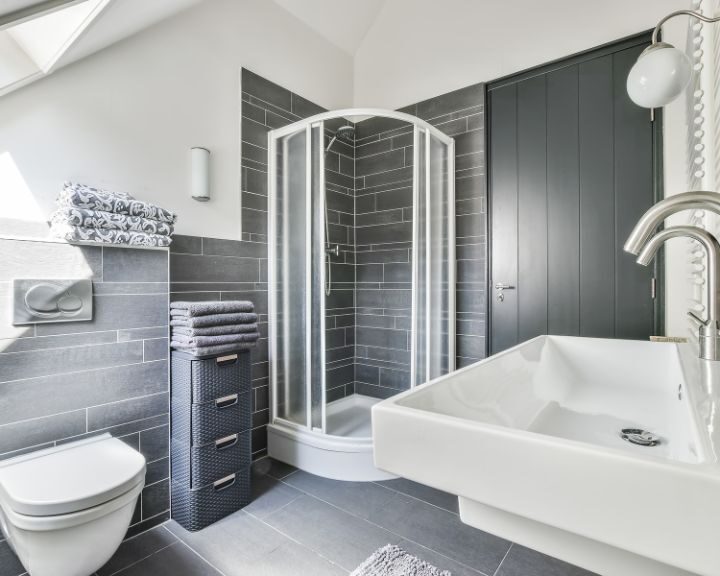 A bathroom design with a grey and white color palette featuring a shower and sink.