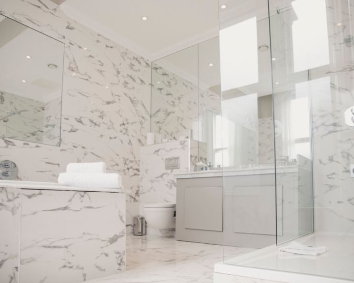 A white marble bathroom tile with a glass shower enclosure in a bustling city.