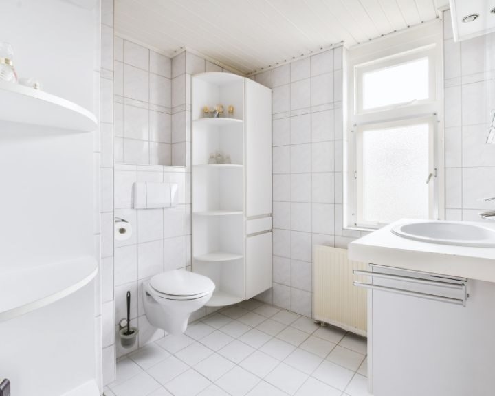 A white bathroom with a toilet, sink, and tile.