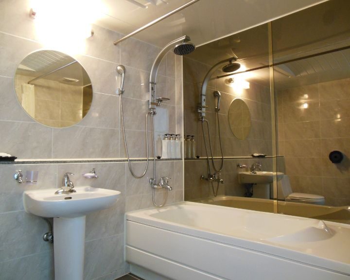 A city bathroom with a bathtub, sink, and mirror.